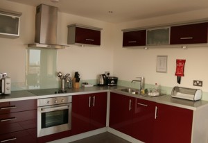 StayManchesterKitchen StayManchester Kitchen Red cupboards, white walls, utensils