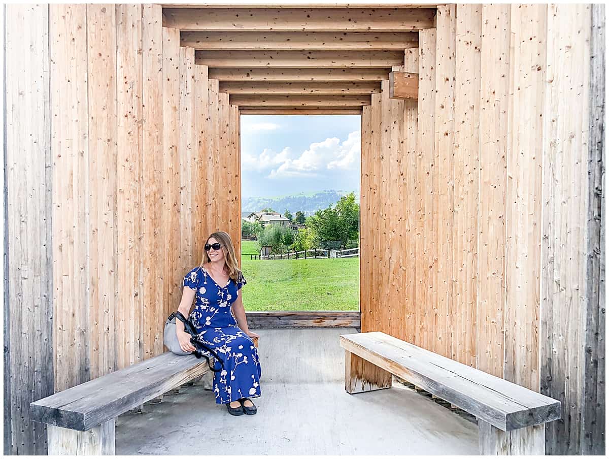 Abigail King sitting in the wooden Krumbach Bus Stop in Austria
