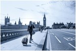 Striding across towards Westminster with a carry on suitcase in London