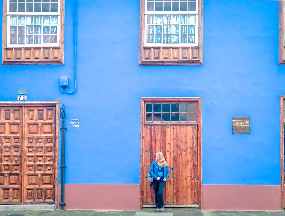 Abigail King outside a colourful blue house in Lisbon - Portugal Road Trip Itinerary