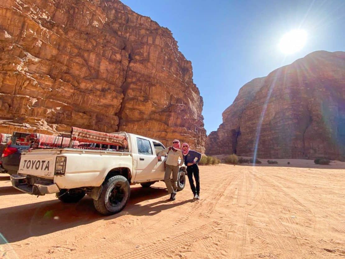 Jordan - desert climate and sunshine - two women dressed in trousers standing by a jeep in Wadi Rum