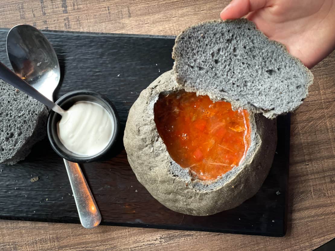 Child lifting the lid off a volcanic bread bowl to reveal lava soup at the Soup Company in Vik, Iceland for lunch.