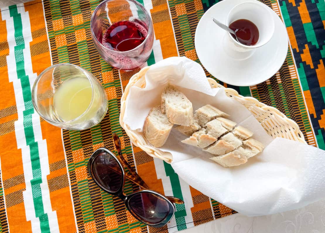 Breakfast platter of traditional Gambian tapalap bread with jam, wonjo juice, baobab juice and sunglasses