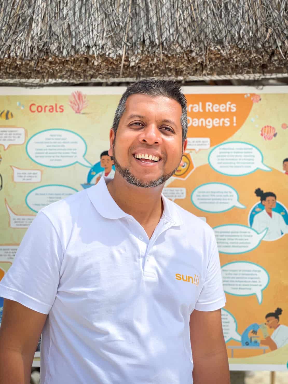 Portrait of Ali Abdool Sustainability Manager at Sunlife in front of the coral regeneration project poster