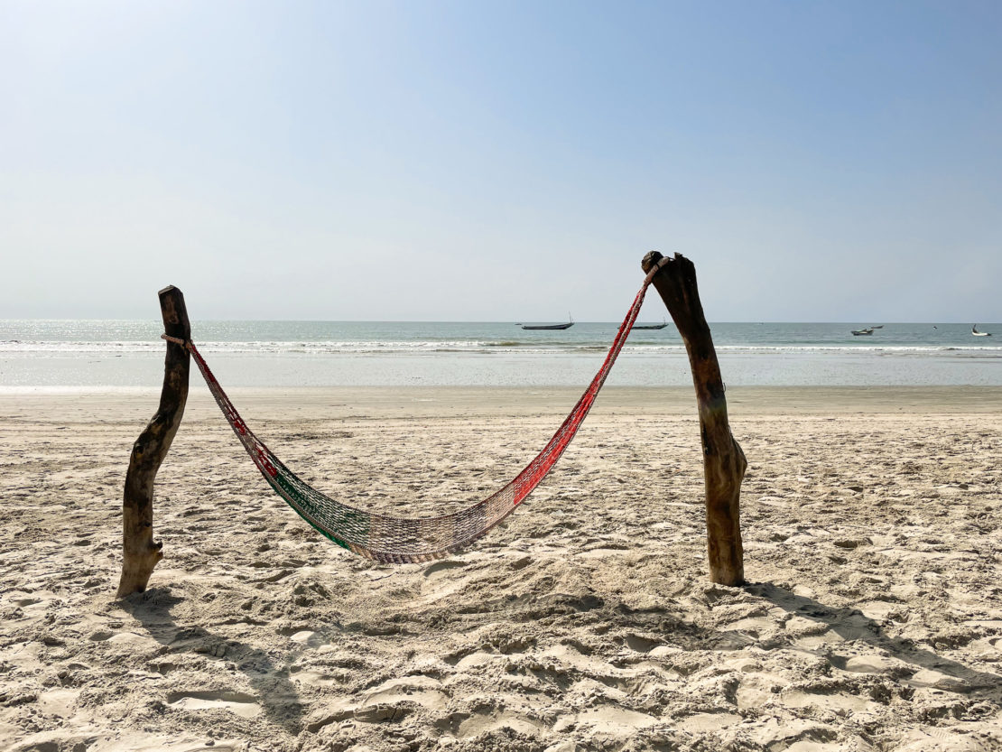 Hammock and driftwood on a sandy beach in The Gambia