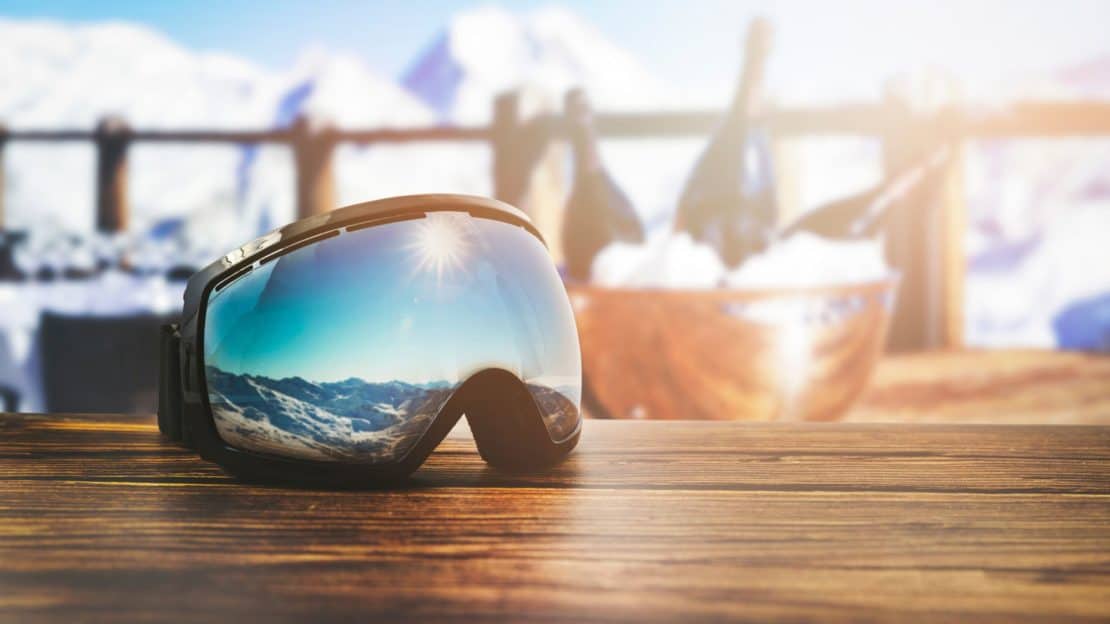 Ski goggles with champagne and snowy landscape in the background