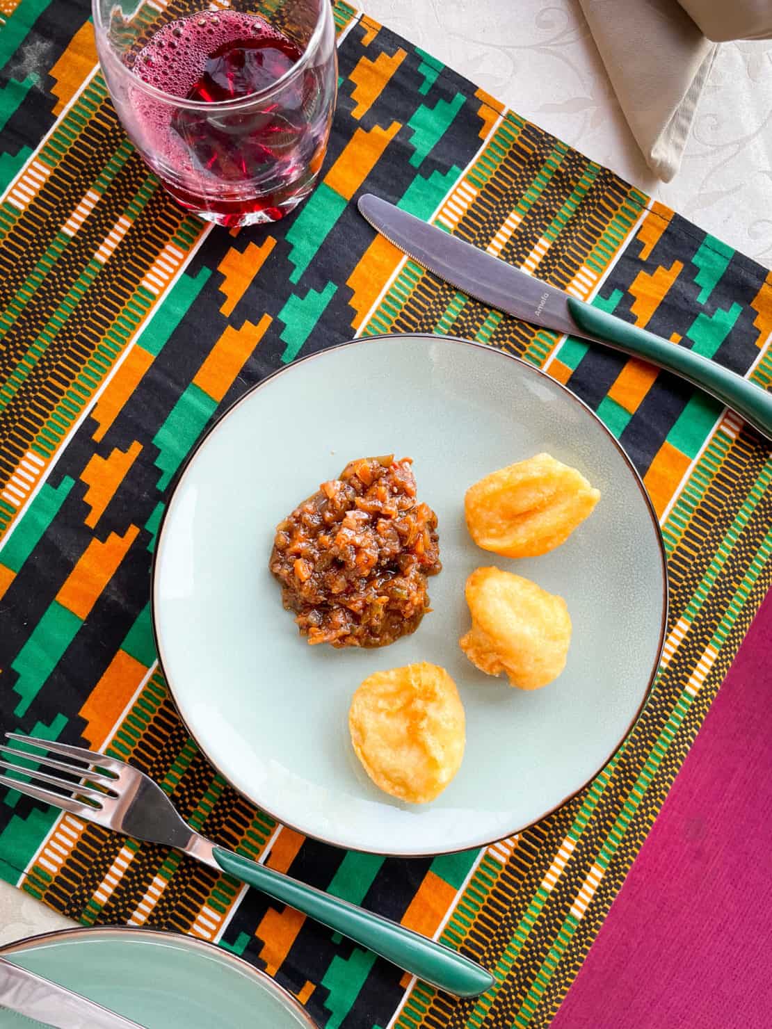 The gorgeous breakfast platter of akara with a chilli, onion and spice sauce on a colourful Gambian table mat