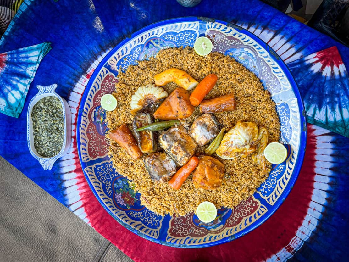 The traditional Gambian meal of benachin served on a decorative blue plate with a side dish of vegetables