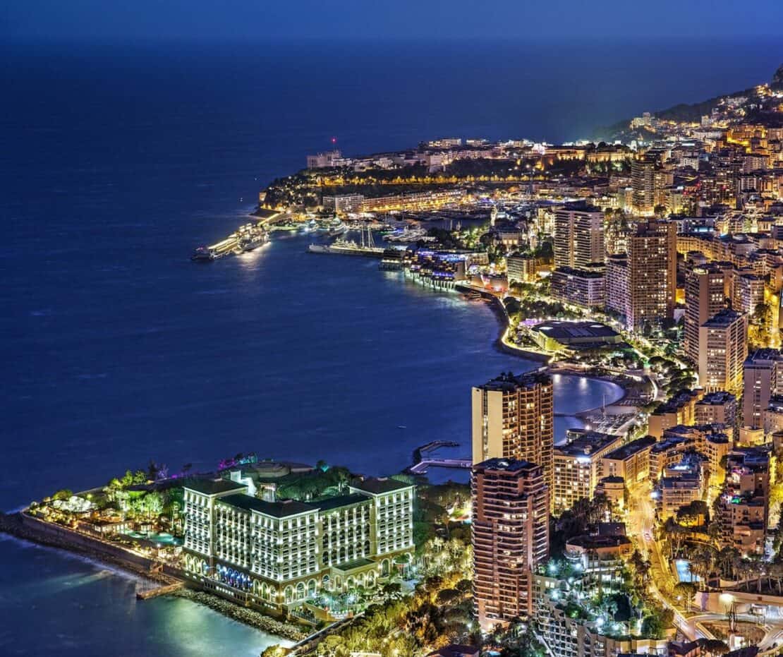 Night scene in Monaco with twinkling lights on the edge of the coast near the Old Town