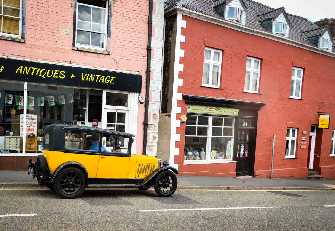 A yellow sports car zooms along a small village in North Wales