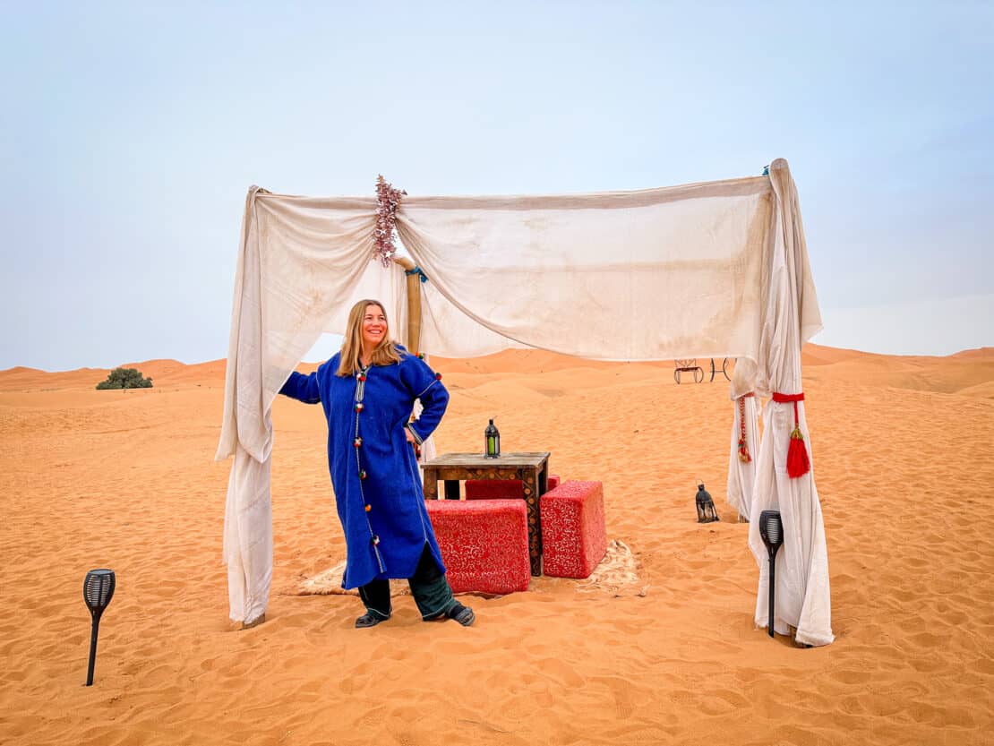 Abigail King in a desert camp with table and chairs in the Erg Chebbi dunes in Morocco
