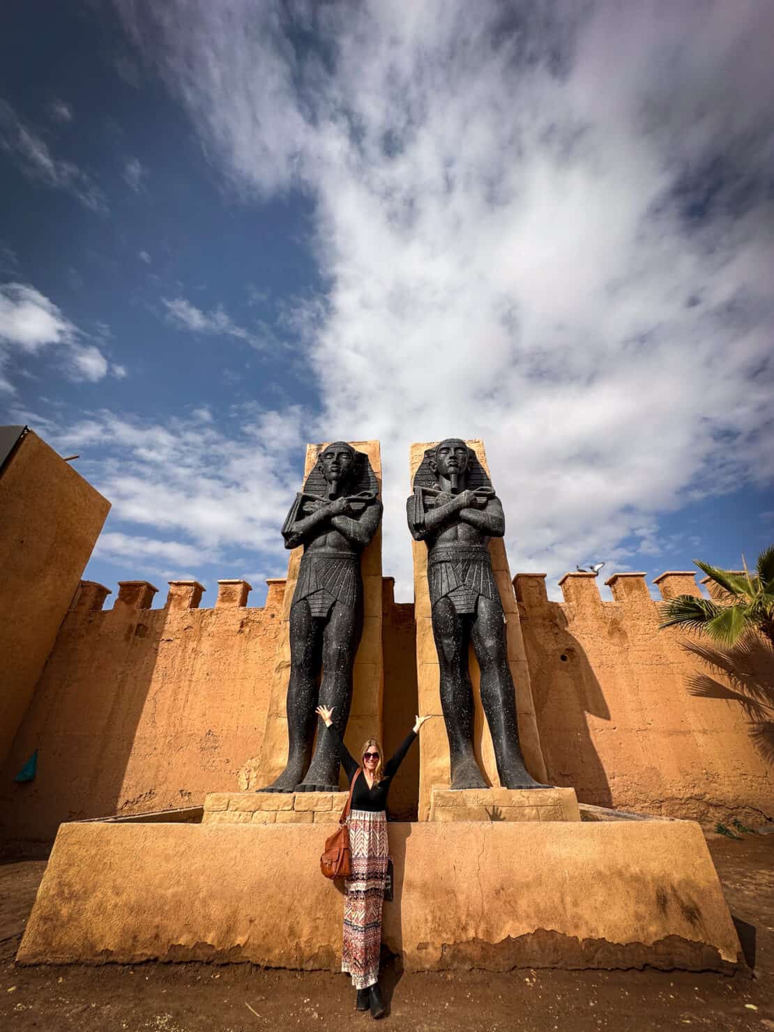 Woman standing by Egyptian statues at the Atlas Film studios near Ouarzazate in Morocco