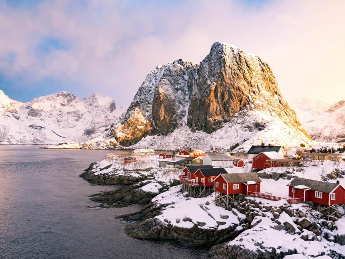 Red houses on stilts in front of a snowy rocky landscape is a great example of the stunning natural scenery that Norway is famous for