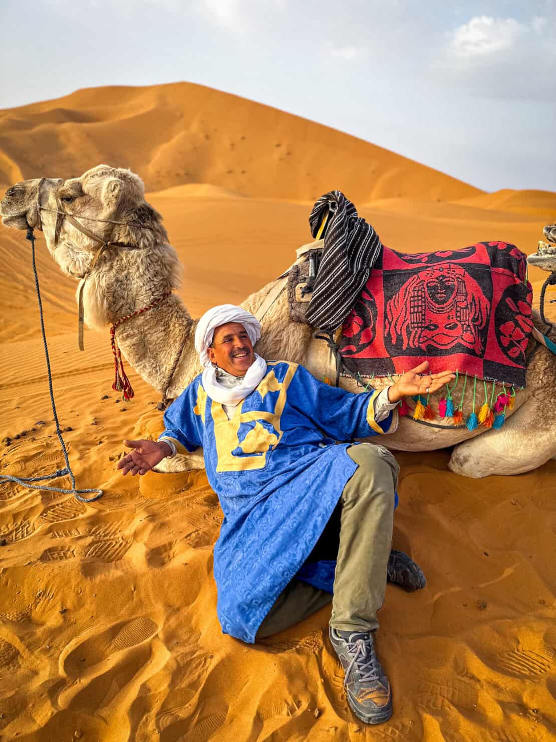 Relaxed Berber man with camel at the Erg Chebbi dunes in Morocco