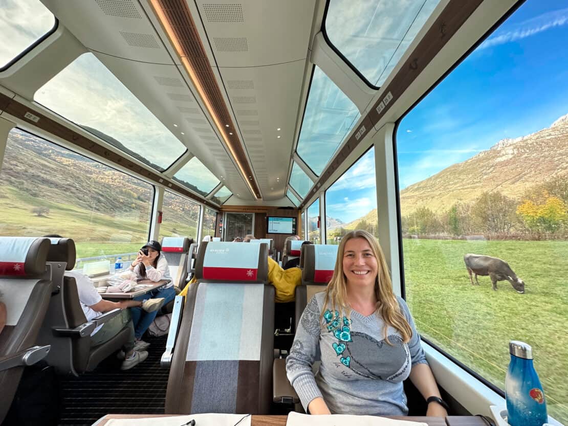 Abigail King on the Glacier Express with a cow in the background