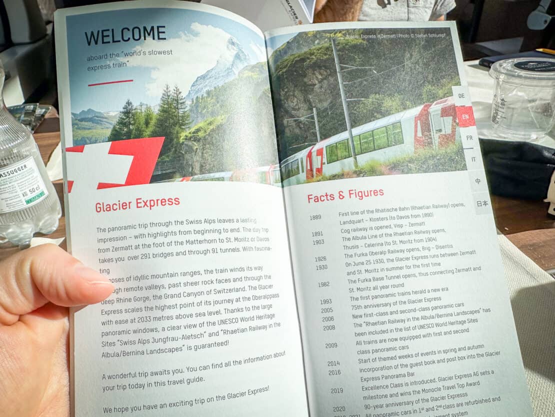 Glacier Express brochure fact page in hand on the train