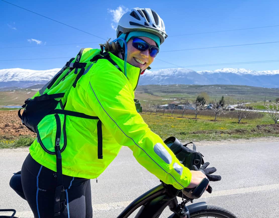 Abigail King cycling next to topped mountains in Albania - cycling in Albania