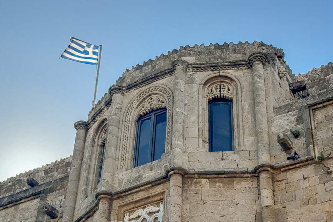 Greek flag flying on an old building in Rhodes, Greece