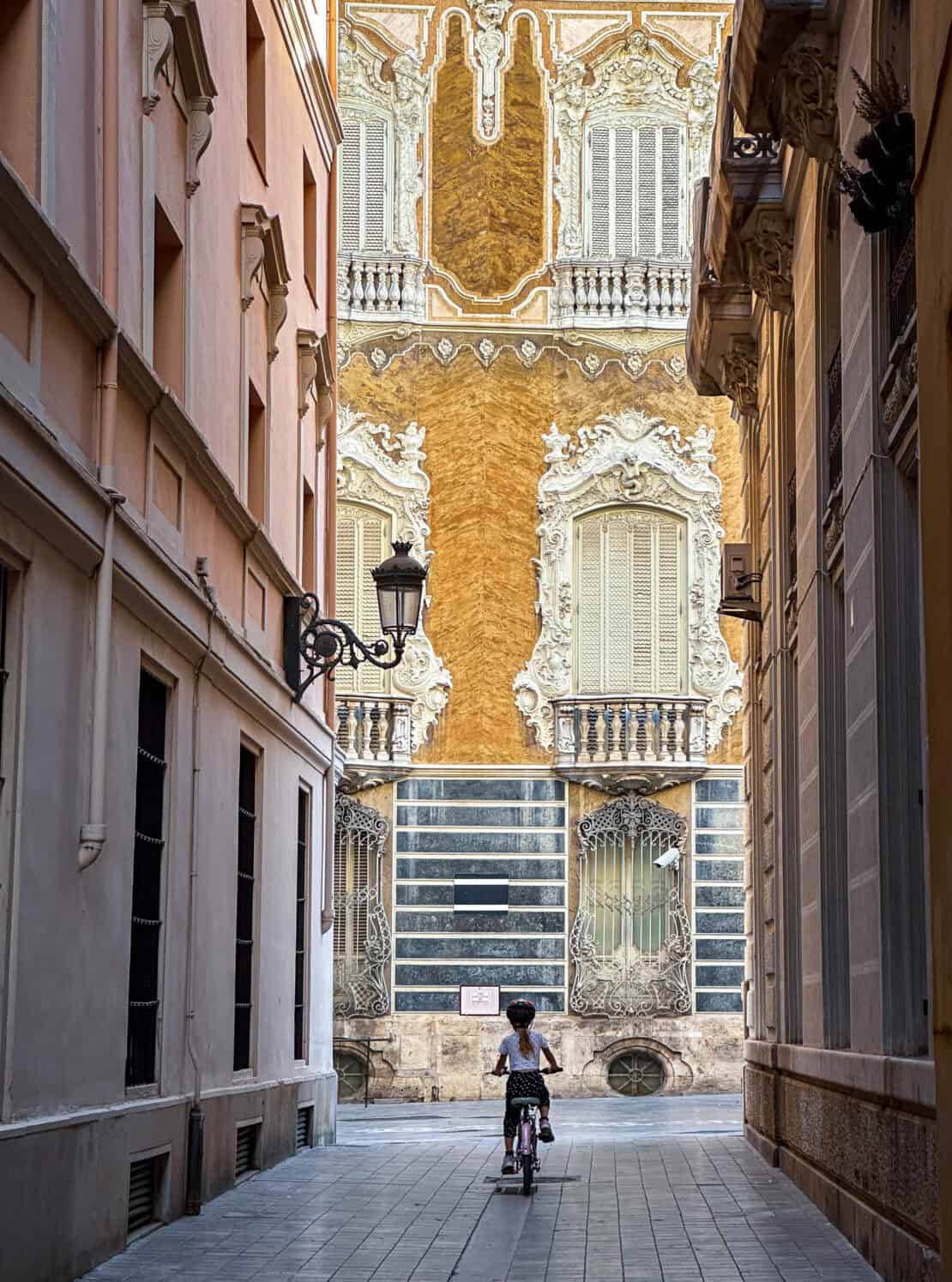 Child cycling through Valencia Old Town Spain