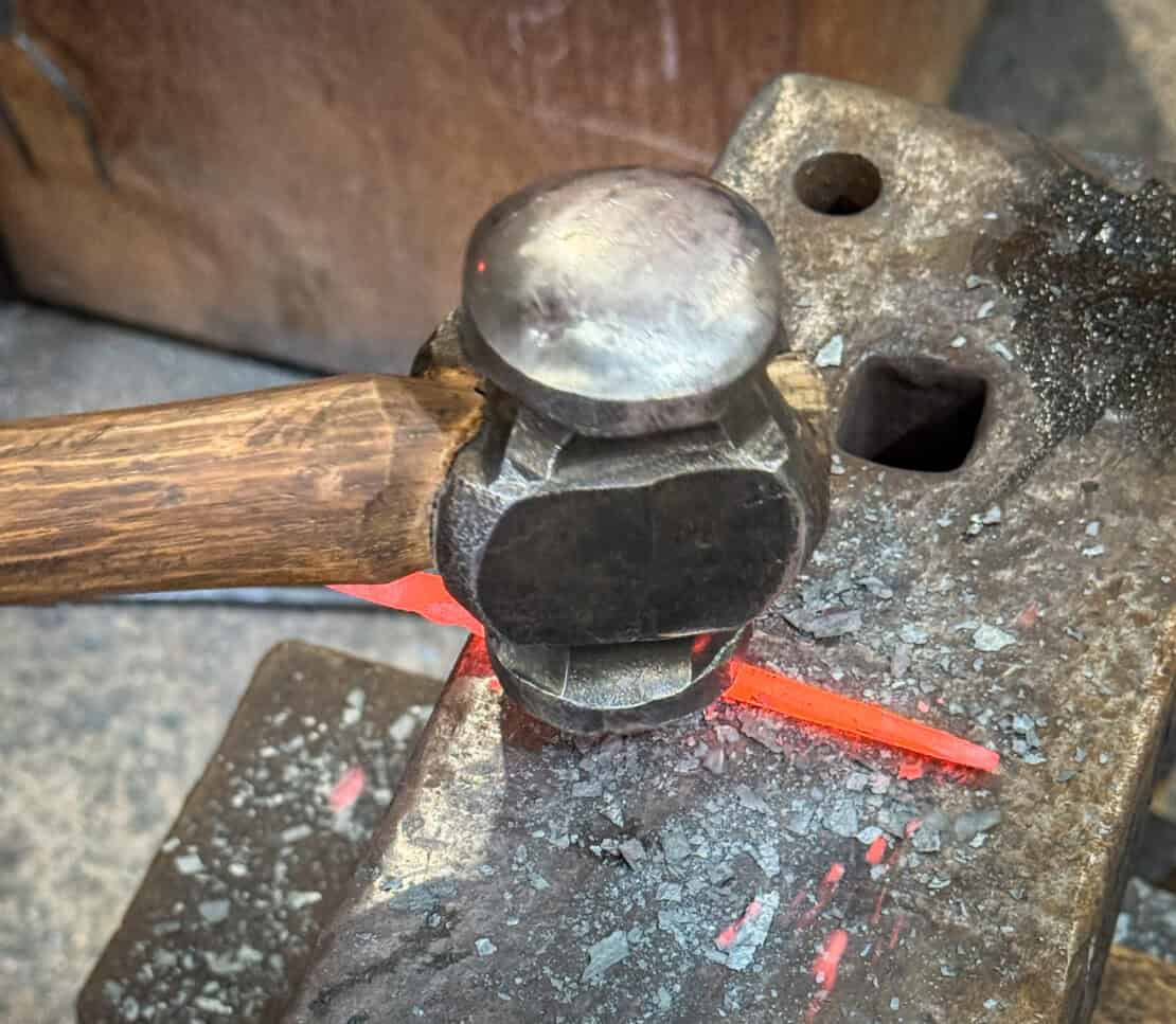 Hot metal being shaped with a hammer during a blacksmithing session at Oldfield Forge in Herefordshire