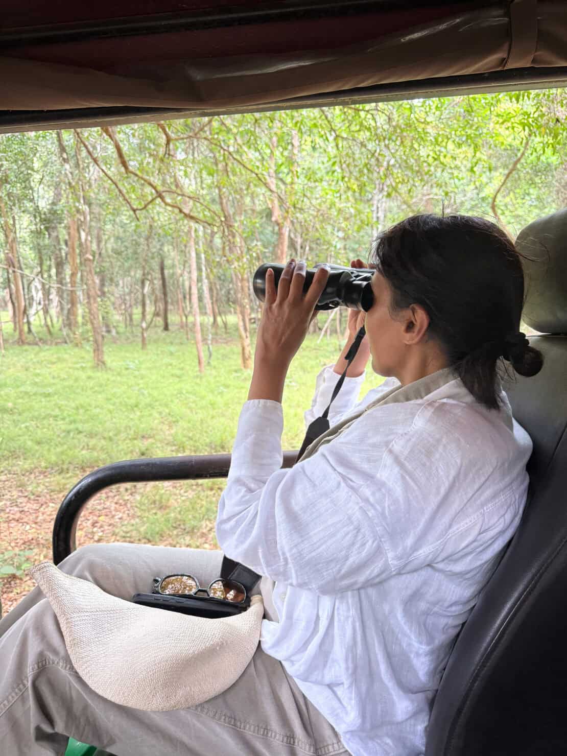 woman looking through binoculars on safari Sri Lanka