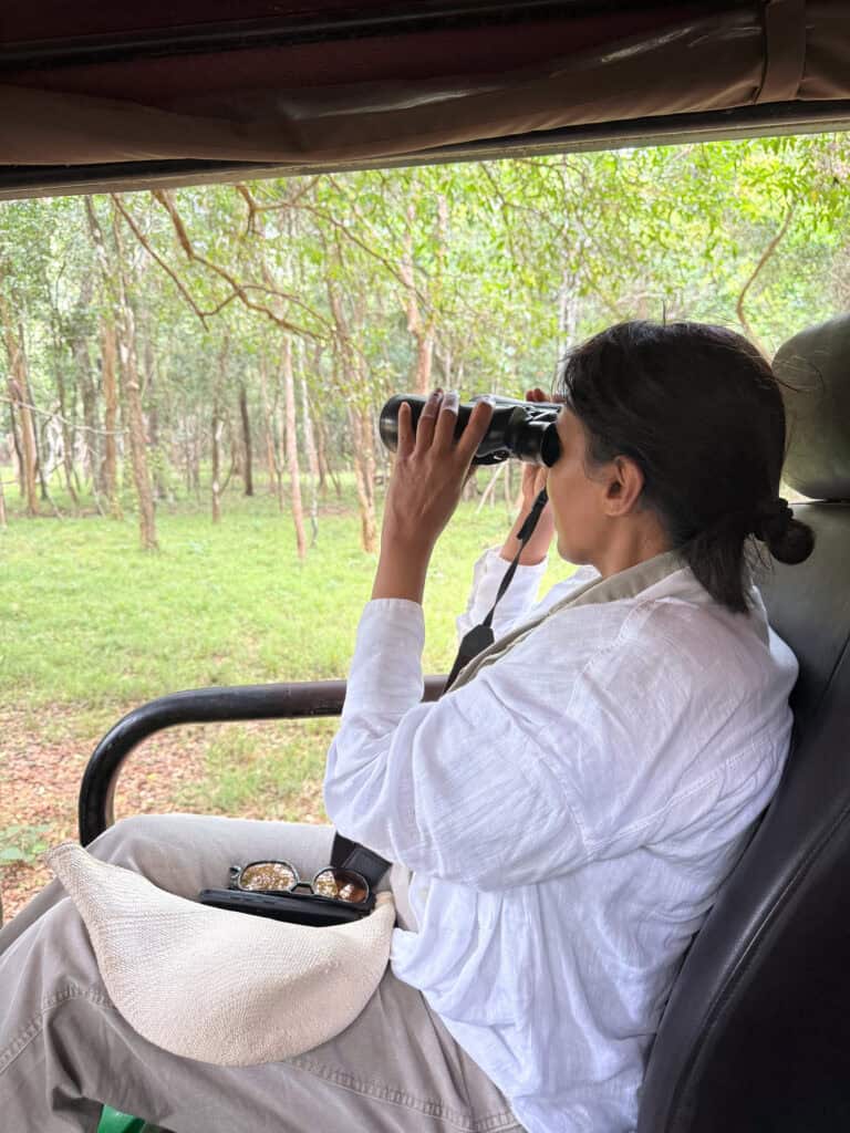 woman looking through binoculars on safari Sri Lanka