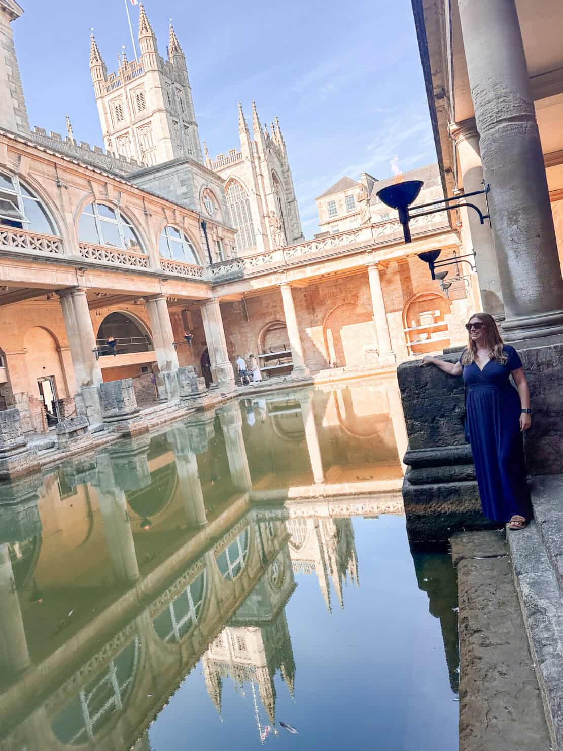 Abigail King standing by the water at the Roman Baths in Bath, England
