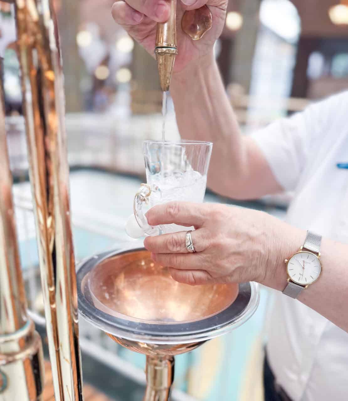 Woman pouring medicinal water in Wandelhalle, Bad Kissingen, Germany