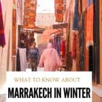 Marrakech medina street lined with colourful Moroccan rugs and textiles, with people walking between the market stalls